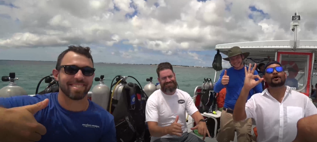 four men on a boat in the water with scuba gear